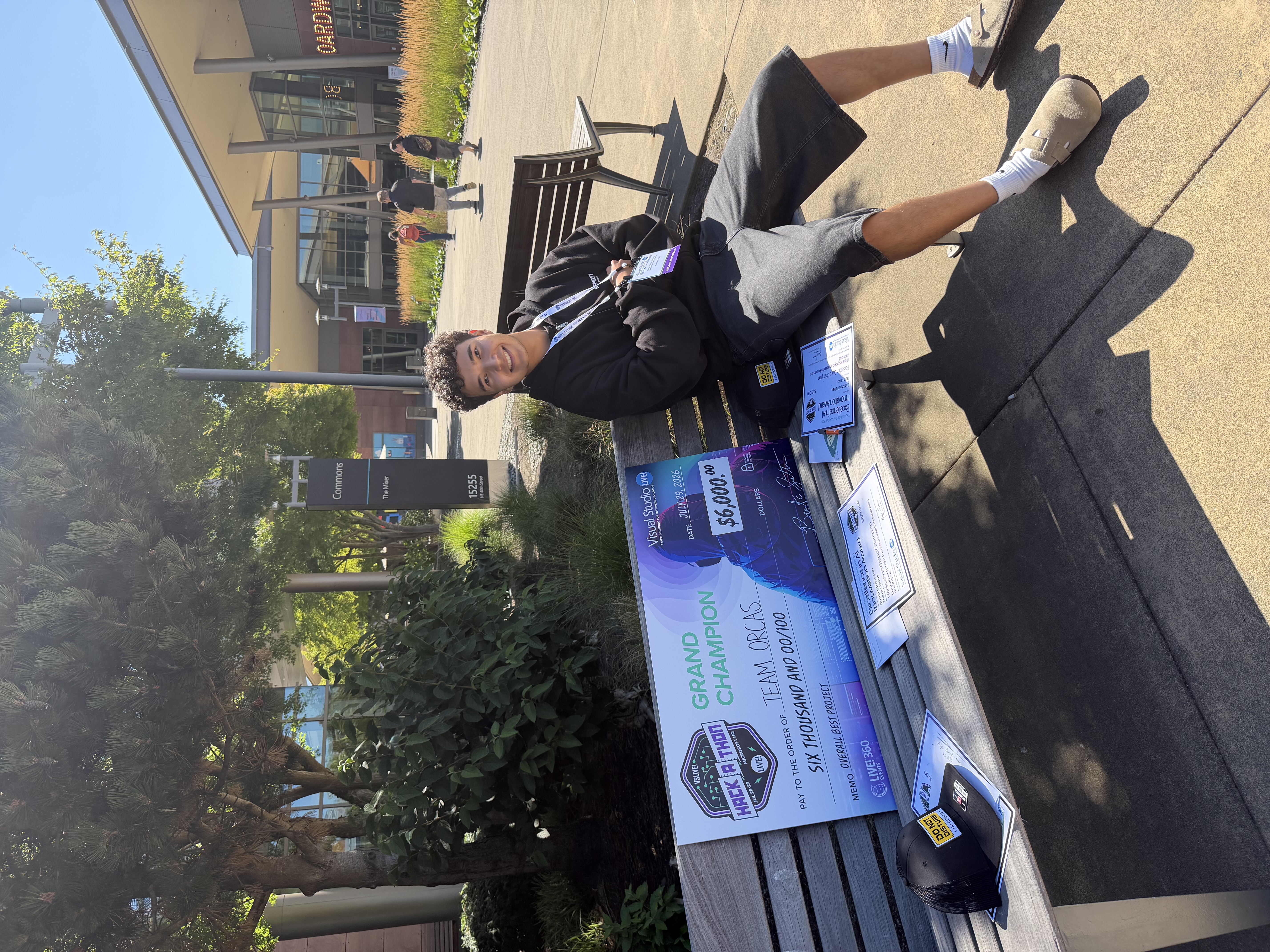 Ilian Khankhalaev seated beside the Grand Champion prize cheque and award certificates at Microsoft headquarters